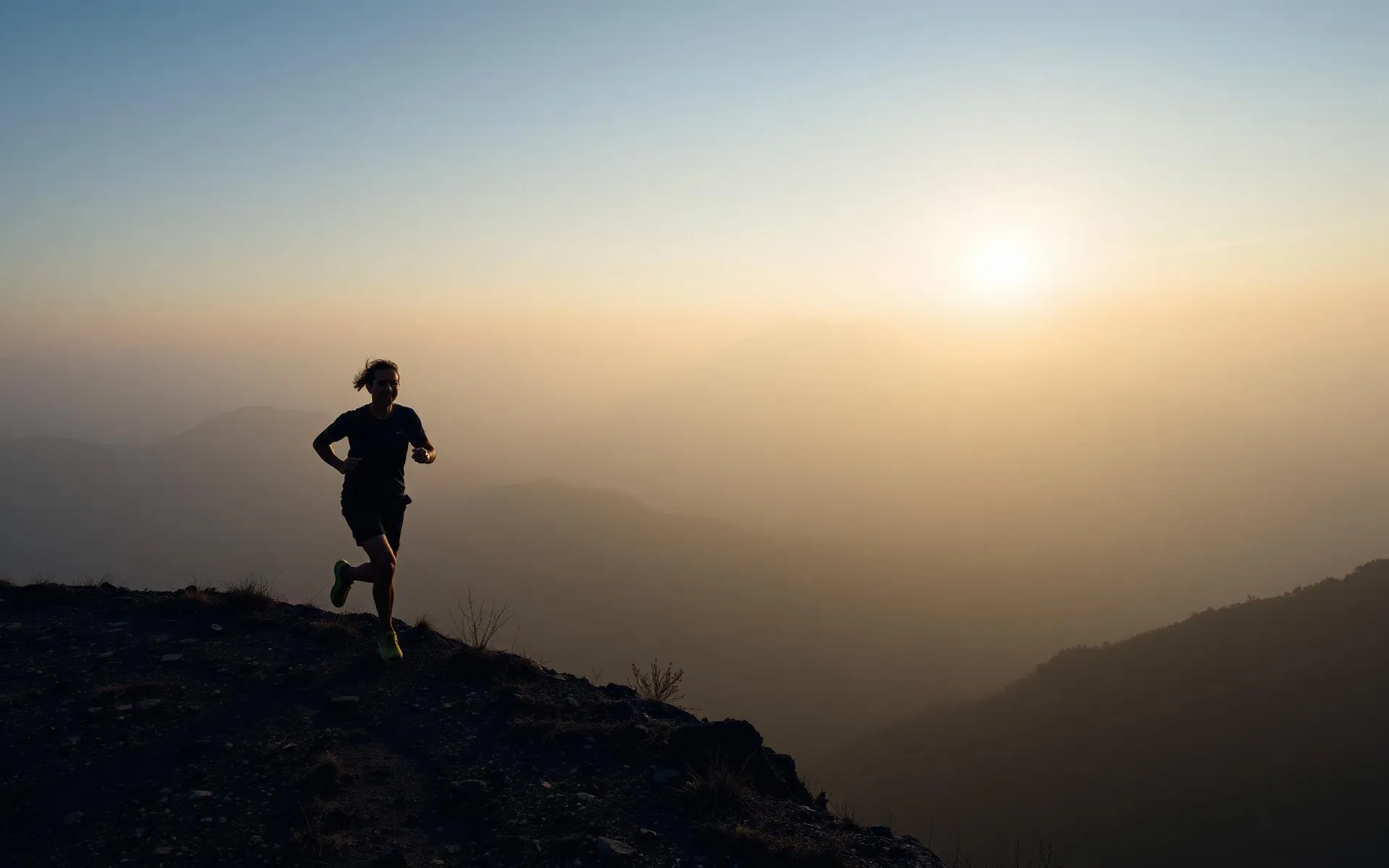 Corredor de trail en una cresta de montaña con niebla al amanecer